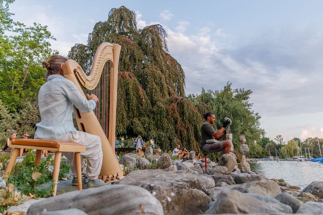 Felix Widrig playing harp beside Greg balancing stones