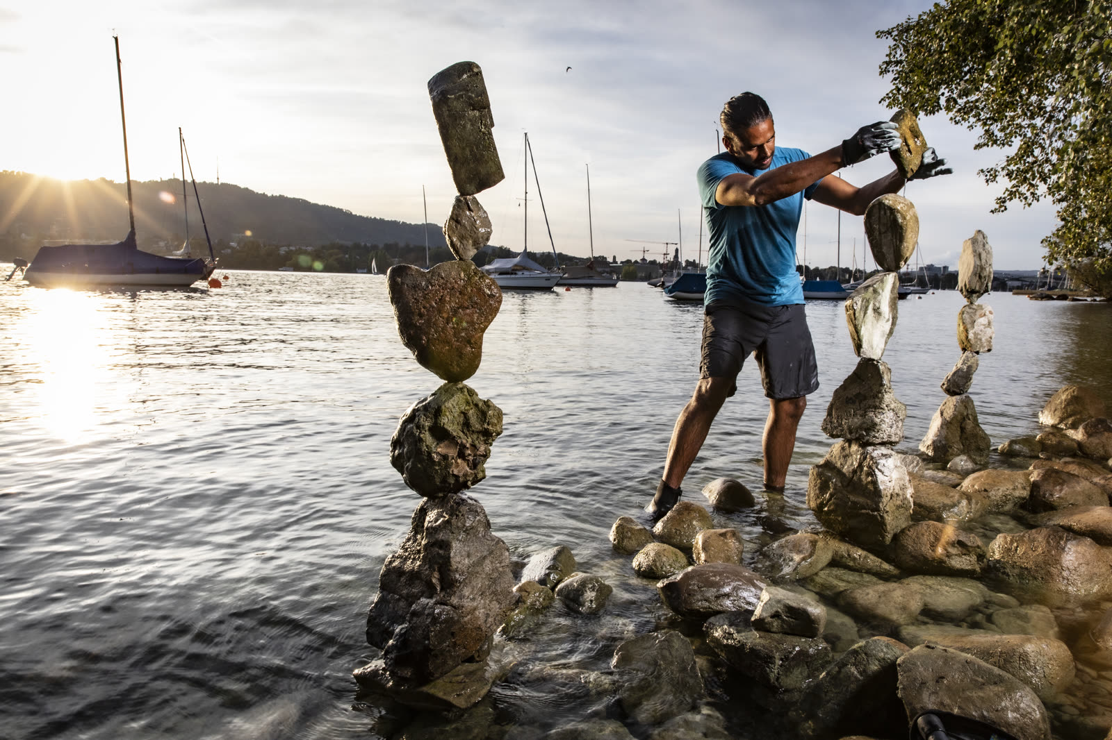 Greg Jagassar building balanced stone towers in Lake Zürich at golden hour